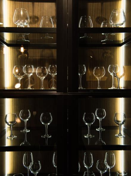 different glasses on shelves in kitchen with dark light